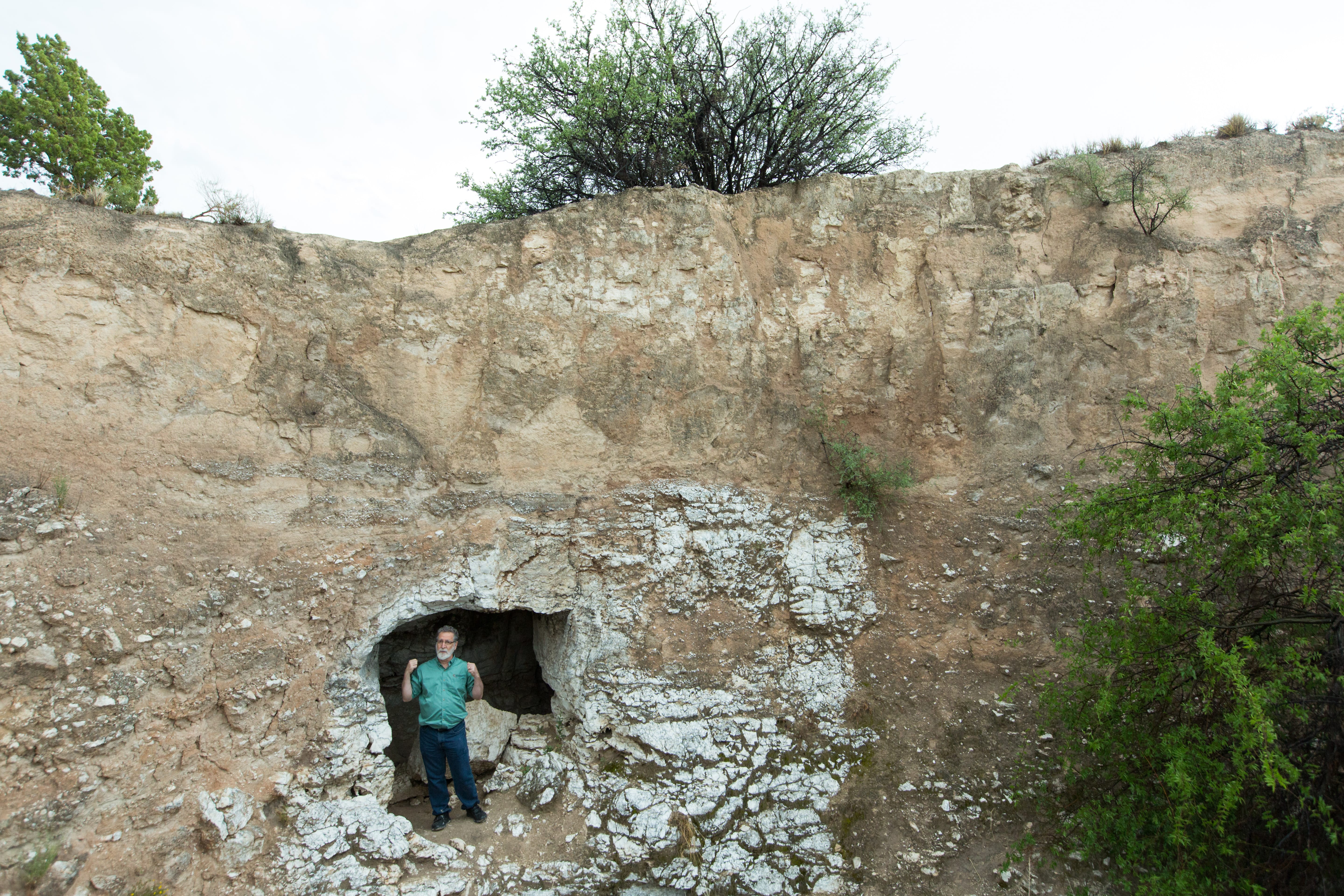 George Veni, executive director of the National Cave and Karst Research Institute, stands above a stream that flows out of Parks Ranch Cave near Carlsbad, N.M. The cave is an example of karst, a porous limestone. (Robin Zielinski for the Center for Public Integrity)